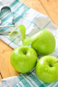 High angle view of wet granny smith apples on tablecloth