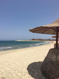 Beach umbrellas at beach against clear sky on sunny day