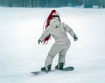 Snowboarder girl is riding a snowboard on the track.