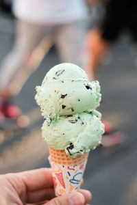 Cropped hand of person holding ice cream cone in city