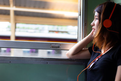 Young woman listening to music while traveling in train