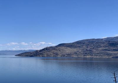 Scenic view of sea and mountains against clear blue sky