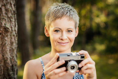 Close-up portrait of woman photographing with camera in forest