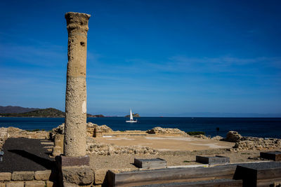 Scenic view of ruins by the sea against blue sky