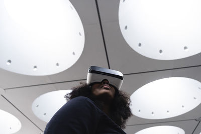 Woman wearing virtual reality simulator under illuminated ceiling