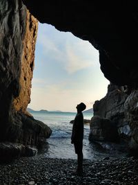 People standing on rock by sea against sky