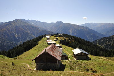 House on field by mountains against sky