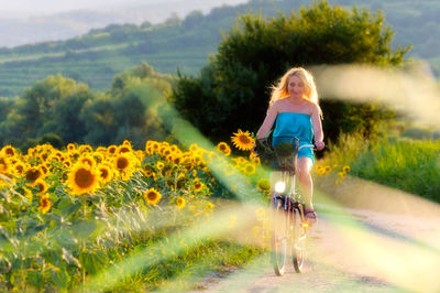 Woman riding bicycle by flowering plants