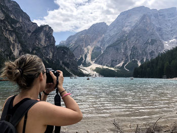 Rear view of woman photographing against mountains