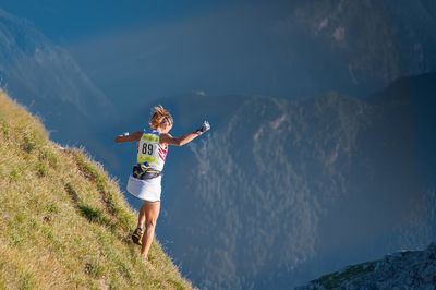 Rear view of man with arms outstretched against mountain range