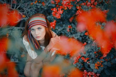 Portrait of young woman standing against yellow flower