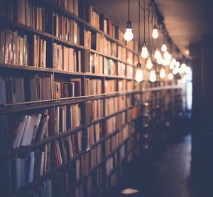 Reflection of illuminated lights on glass in building filled with books