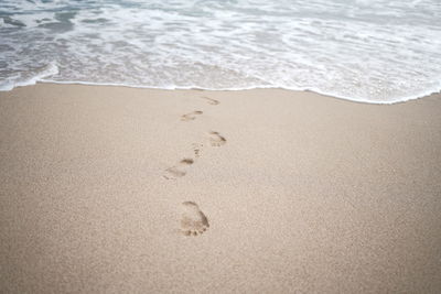 Footprints on the white sand of the beach.