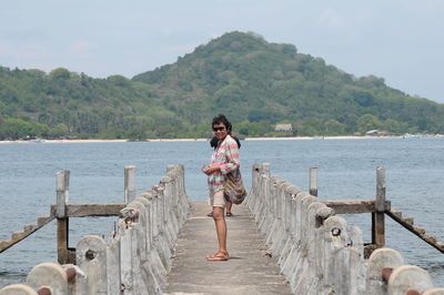 Portrait of woman standing on pier at against mountain