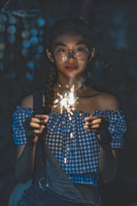 Portrait of young woman holding eyeglasses