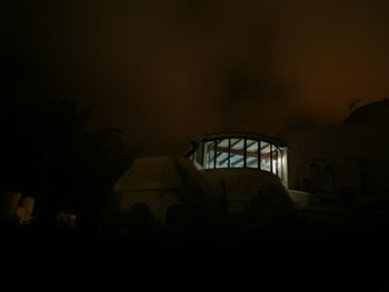 Silhouette people in illuminated building against sky at night