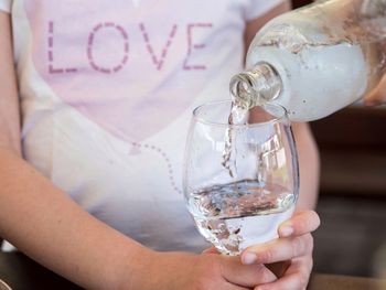 Close-up of girl hand holding glass while water is poured