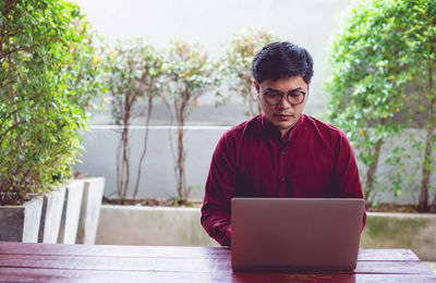 Young man using mobile phone while sitting on table