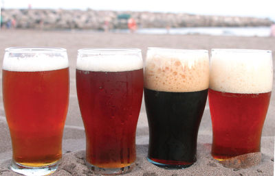 Close-up of beers on sand at beach