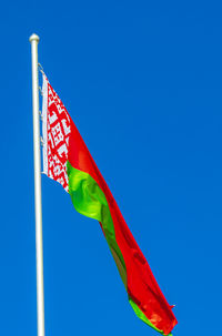 Low angle view of flag against clear blue sky