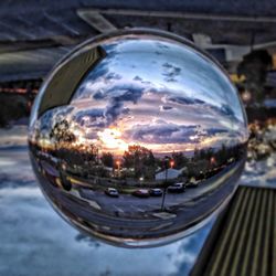 Close-up of crystal ball on glass against buildings in city