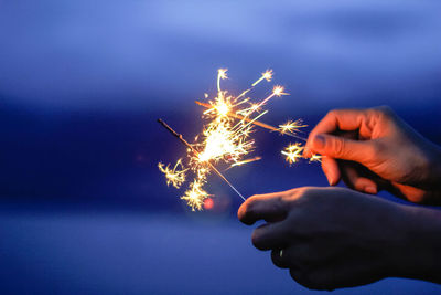 Low angle view of hand holding firework display at night