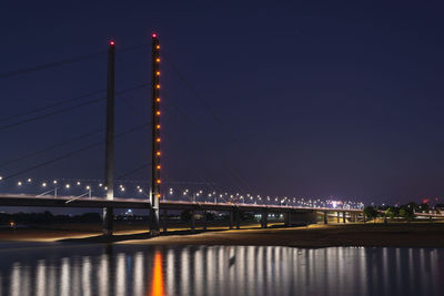Illuminated bridge over river at night