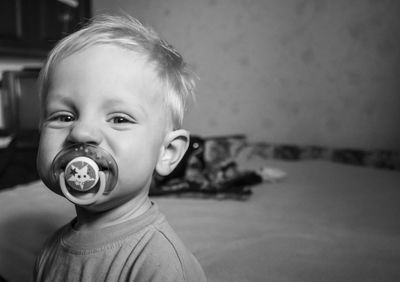 Portrait of boy with pacifier in mouth at home