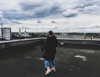 Rear view of woman standing on bridge against sky