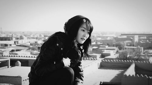 Portrait of woman with dog against sky in city