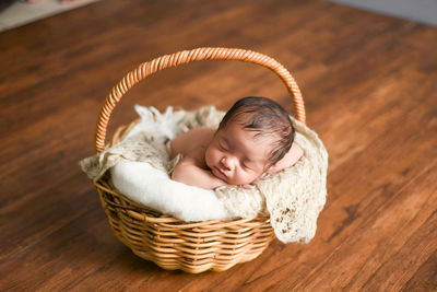 Close-up of cute baby boy in wicker basket on table
