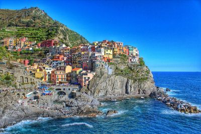 Scenic view of sea by buildings against clear blue sky