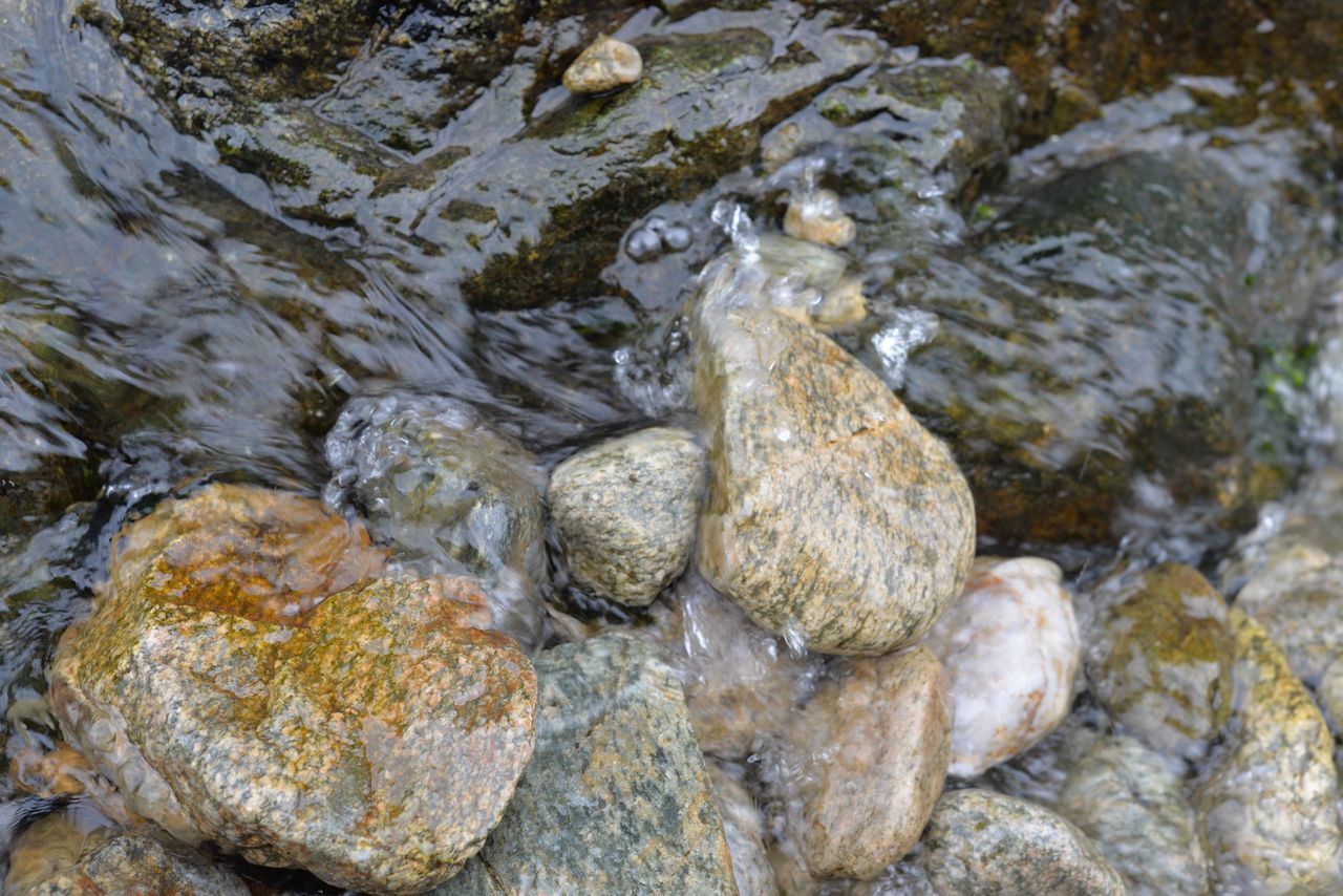 HIGH ANGLE VIEW OF ROCKS BY RIVER