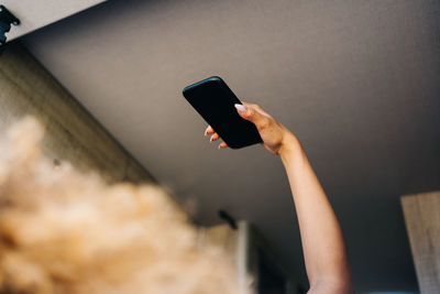 Anonymous woman with afro hairstyle lying upside upon bed in trailer and browsing mobile phone on sunny summer day