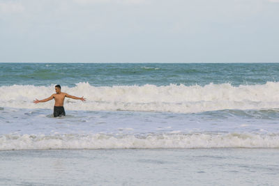 Shirtless man enjoying in sea against sky