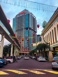 Traffic on city street by buildings against sky