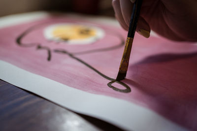 Closeup view of crop unrecognizable female artist creating picture with paint and brush on canvas in workshop
