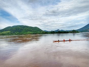 People in boat on mountain against sky