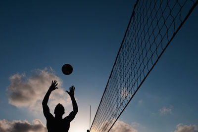Silhouette man playing volley ball against sky