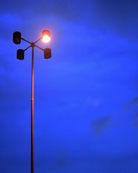 Low angle view of illuminated street light against blue sky