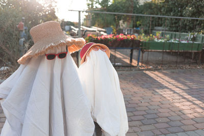Trendy sheet ghosts costumes on little kids standing on a suburbs street. happy halloween holiday
