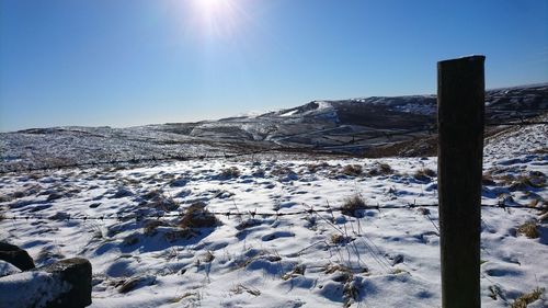 Scenic view of snow covered mountains against clear blue sky