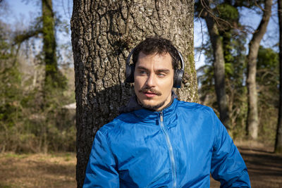 Beautiful man with blue eyes and mustache listening to music while exercising.