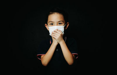 Portrait of boy holding camera over black background