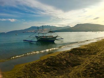 Sailboats moored in sea against sky