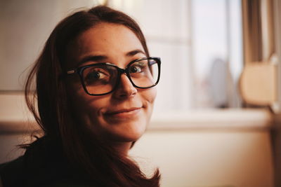 Close-up of smiling young woman wearing eyeglasses looking away at home