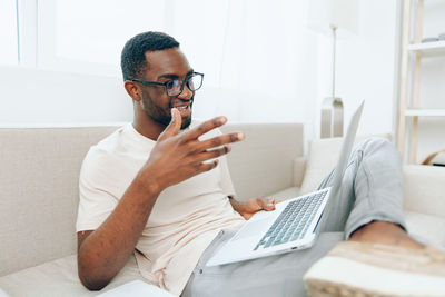 Young man using mobile phone while sitting at home