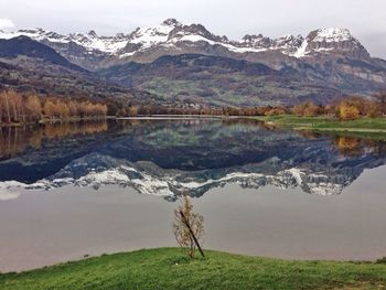 Refection of snow mountains on calm lake against sky