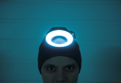 Portrait of person wearing illuminated headwear against wall