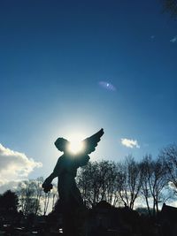 Low angle view of silhouette statue against sky during sunny day